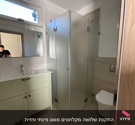 מקלחון זכוכית עם דלתות מתכת בחדר אמבטיה
